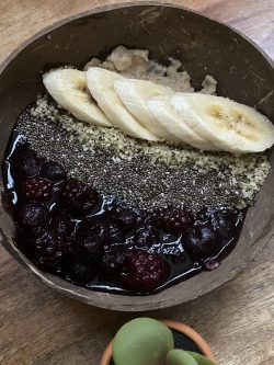 Oatmeal breakfast bowl. Topped with cooked berries, banana, chia seeds and hemp seeds.